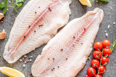 Arkaplanda baharatlar olan çiğ balık filetosu.