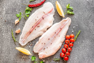 Arkaplanda baharatlar olan çiğ balık filetosu.