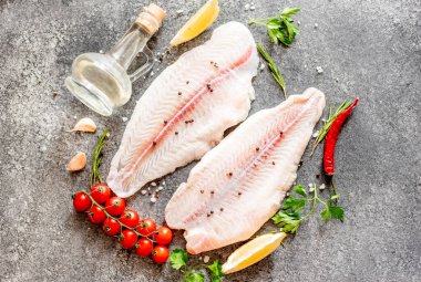 Arkaplanda baharatlar olan çiğ balık filetosu.