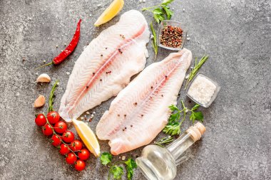 Arkaplanda baharatlar olan çiğ balık filetosu.