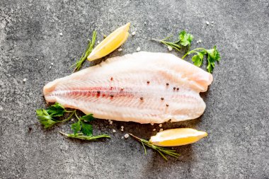 Arkaplanda baharatlar olan çiğ balık filetosu.