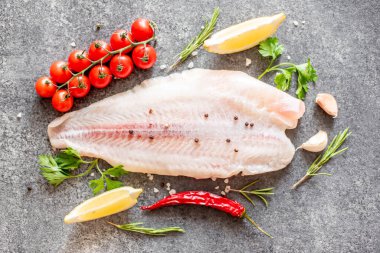 Arkaplanda baharatlar olan çiğ balık filetosu.