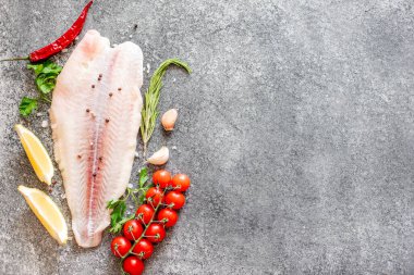 Arkaplanda baharatlar olan çiğ balık filetosu.