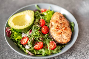 Avokado ve sebze salatalı ızgara somon bifteği.