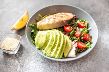 Avokado ve sebze salatalı ızgara somon bifteği.