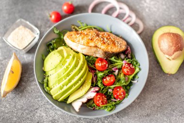 Avokado ve sebze salatalı ızgara somon bifteği.