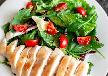 Beyaz tabakta sebzeli ızgara tavuk göğsü.