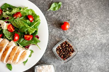 Beyaz tabakta sebzeli ızgara tavuk göğsü.