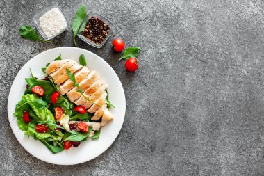 Beyaz tabakta sebzeli ızgara tavuk göğsü.