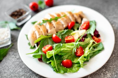 Beyaz tabakta sebzeli ızgara tavuk göğsü.