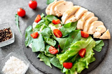 Beyaz tabakta sebzeli ızgara tavuk göğsü.