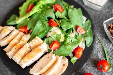 Beyaz tabakta sebzeli ızgara tavuk göğsü.