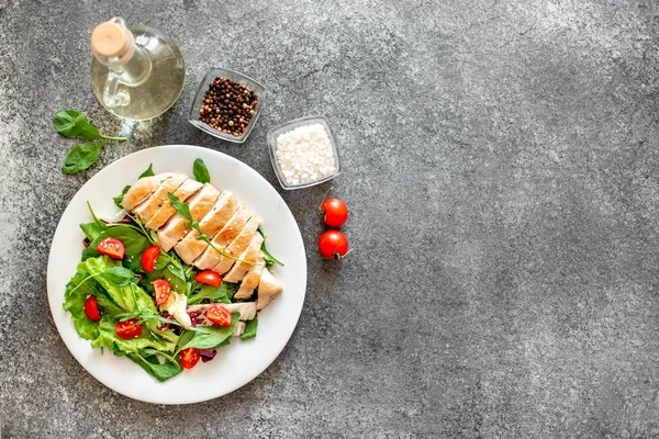 Beyaz tabakta sebzeli ızgara tavuk göğsü.