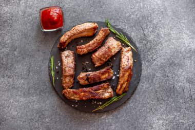 Baharatlı ızgara domuz pirzolası ve gri arka planda otlar.