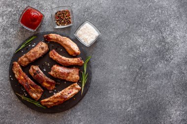 Baharatlı ızgara domuz pirzolası ve gri arka planda otlar.