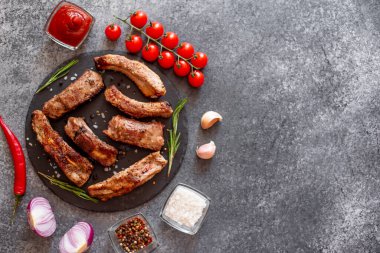 Baharatlı ızgara domuz pirzolası ve gri arka planda otlar.