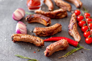 Baharatlı ızgara domuz pirzolası ve gri arka planda otlar.