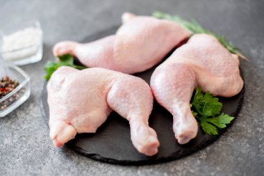 Ahşap bir tahtada çiğ tavuk budu, baharat ve otlarla kaplayın.