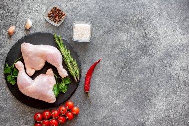 Tahta tahtada otlar ve baharatlarla çiğ tavuk bacakları manzarası, metnin için boş yer.