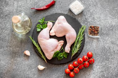 Tahtadaki çiğ tavuk bacakları, baharatlar ve zeytinyağı manzarası.