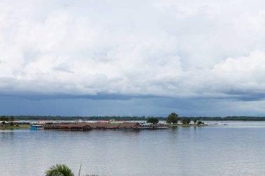 Kumsal ve su köşkü çok uzaklardan görünüyor. Siyah yağmur bulutları gösteriliyor