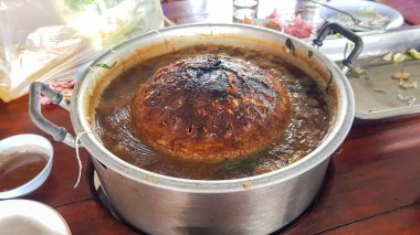 Açık büfe bir tava kullanarak mangal ızgarasında kızartılıyor. Tavada kalanlar siyaha boyanmıştı. Tayland 'da buna Moo Krata denir..