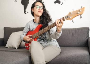 Latin kız evde bassla çalışmaktan zevk alıyor. Seçici odak