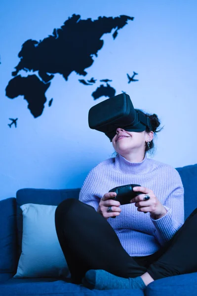 Young woman playing games with virtual reality headset and joystick. Vertical shot