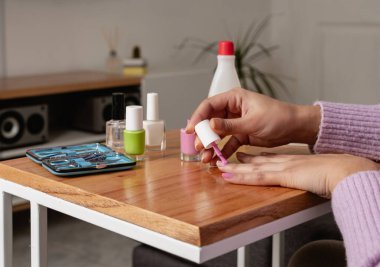 Woman applying pink nail polish at home. Close up image