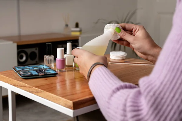 Woman using nail polish remover while doing manicure at home. Close up image