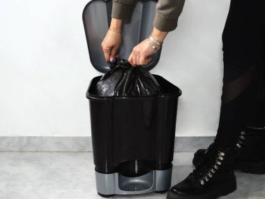 Closing garbage bin plastic bag at home. Unrecognizable person