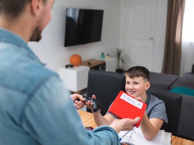 Young boy rewarded with video games for finishing his Spanish homework to his father.