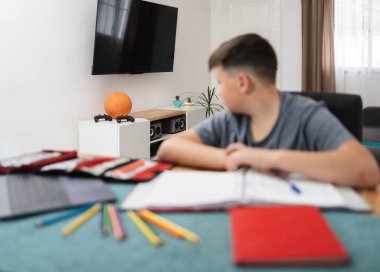 Schoolboy impatient for playing games while doing homework. Selective focus