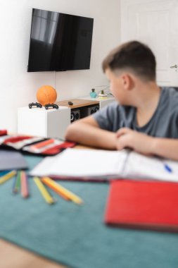 Kid loses concentration while doing homework because he wants to play games. Vertical photography