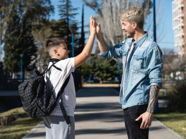 Father and son giving high five on the way to school on a beautiful sunny day