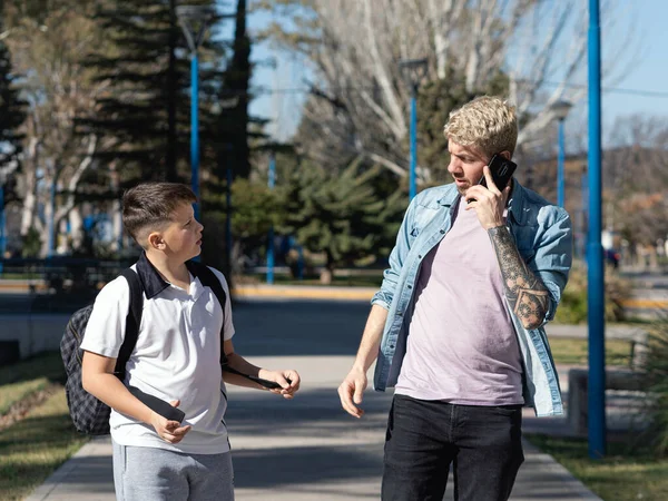 Busy single parent talking on the phone while kid tries to talk to him on their way to school
