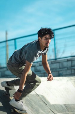 Latin skater boy riding his skate on a sunny day. Vertical photo