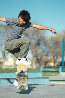 Latin American skater boy doing trick with skate board. Close up. Vertical photo