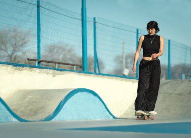 Cool girl riding her skateboard concentrated in the skate park. Copy Space