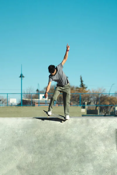Skater doing trick on skate park concrete bowl. Vertical photo