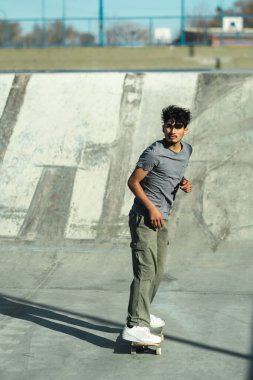 Latin American skater riding in the downtown skate park. Vertical photo