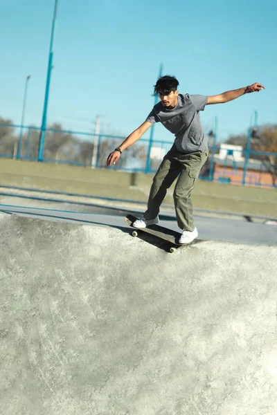 Hispanic skate boarder riding on skate park bowl. Vertical photo