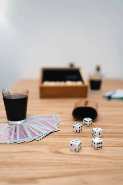 Rolling dices and playing cards on wooden table with cup of coffee. Vertical photo. Close up caption