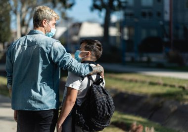 Baba, oğlunun virüs bulaşmasını önlemek için maske takmasını kabul ediyor. Boşluğu Kopyala