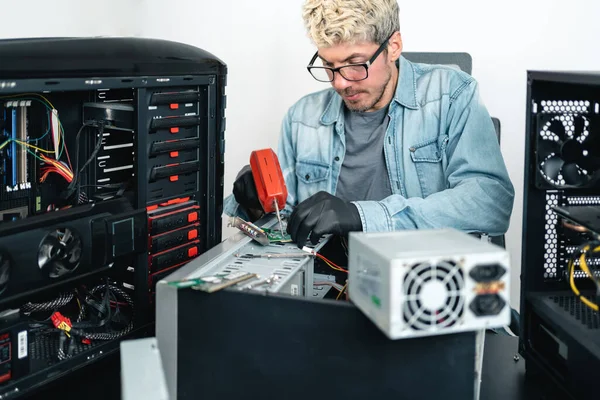 Man welding desktop computer parts while doing pc repairing service