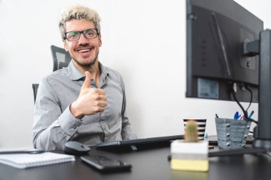 Ofisteki masada oturmuş gülümseyen mutlu iş adamı..