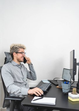 Genç adam telefonda konuşurken ve gülümserken ev işi yapıyor. Dikey fotoğraf