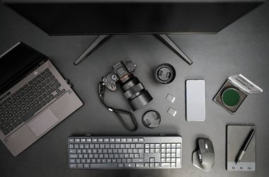 Kamera, bilgisayar, lens, mobil, grafik tablet ve aksesuarlı fotoğrafçı iş yerinin üst görüntüsü. Siyah arkaplan