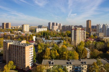 Günümüz modern şehir evlerinin panoramik manzarası açık bir Ekim gününde, renkli yapraklar ve mavi gökyüzü ile sonbahar ağaçları arasında. Reutov, Moskova bölgesindeki kentsel peyzaj kavramını ve kopyalama alanını