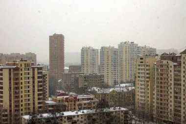 Moskova 'da bulutlu bir kış gününde çatıları karla kaplı modern çok katlı binalarla panoramik bir şehir manzarası.